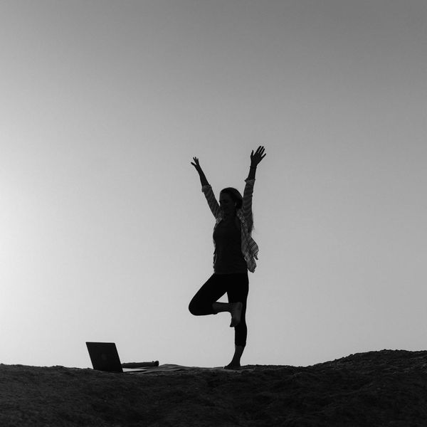 Silhouette of a person in a yoga pose against a sunrise.